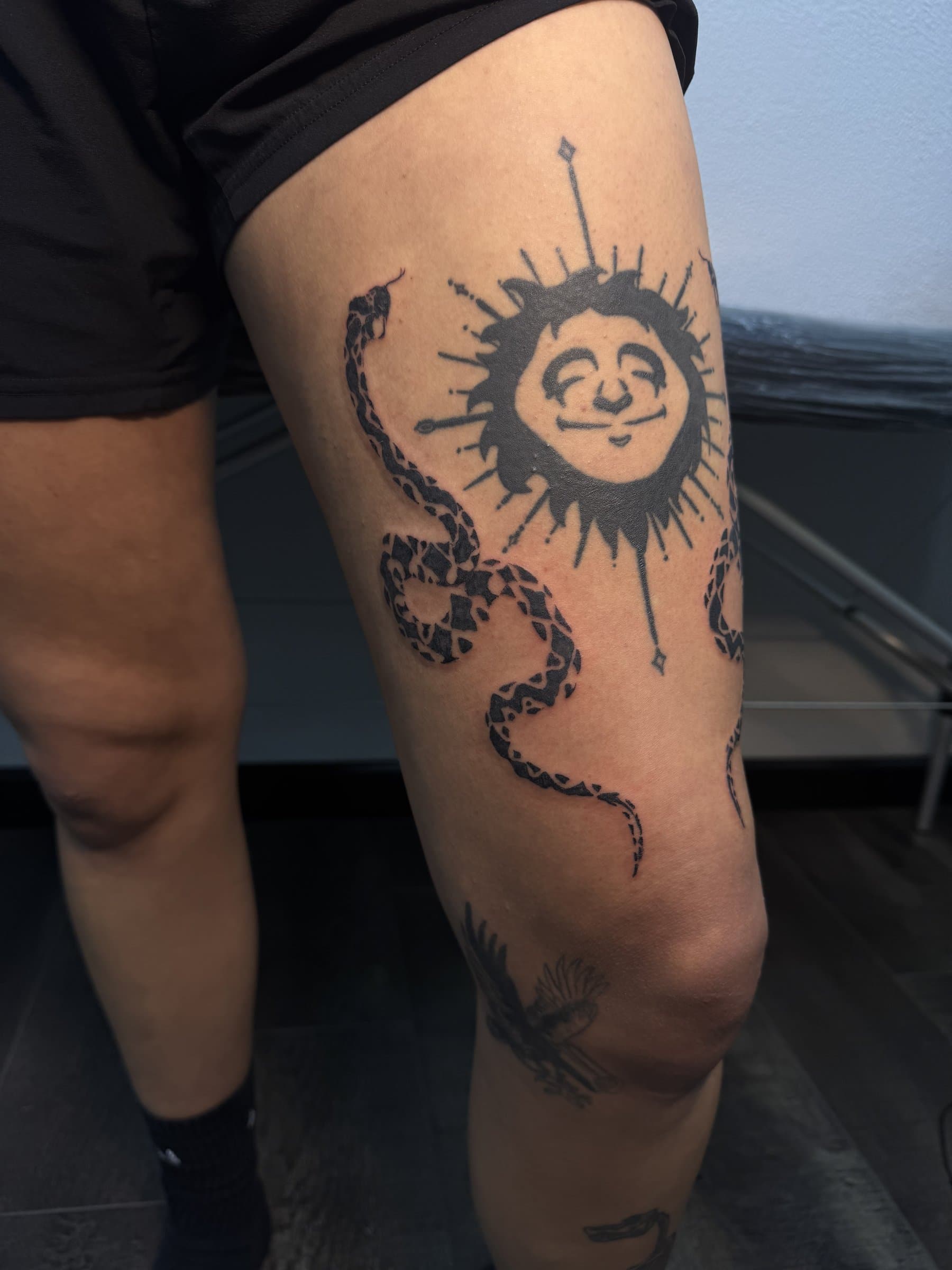 Black-ink serpent and sun thigh tattoo by Will